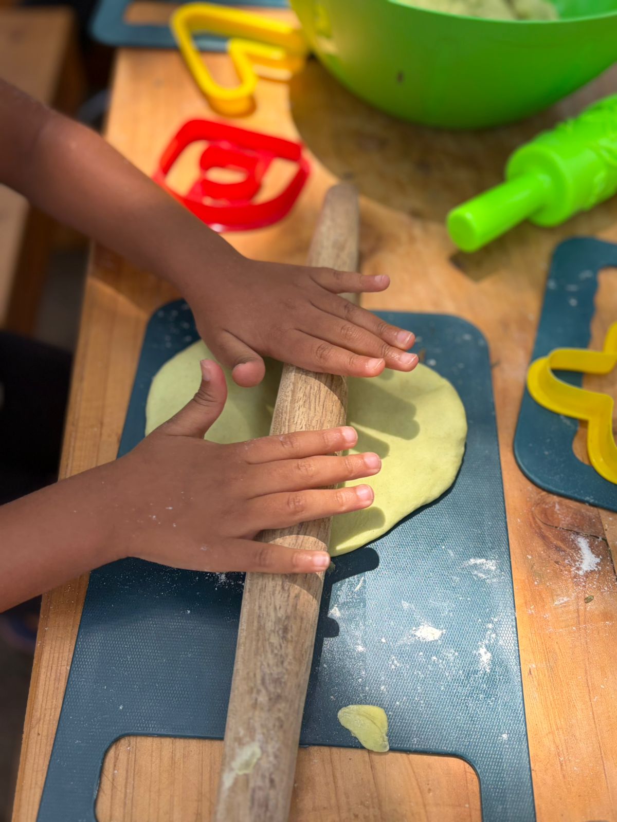 Children rolling dough together with cookie cutters