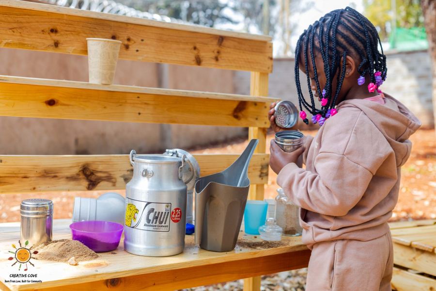 A child playing at the outdoor mud kitchen