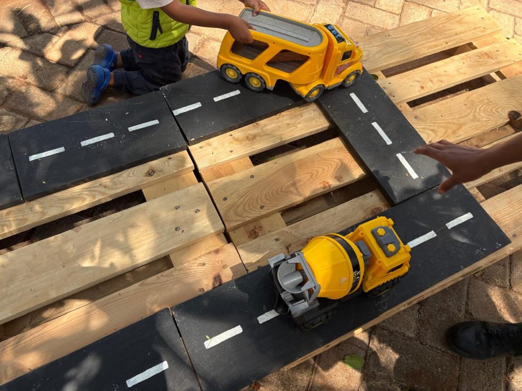 Children playing with toy trucks on a wooden road